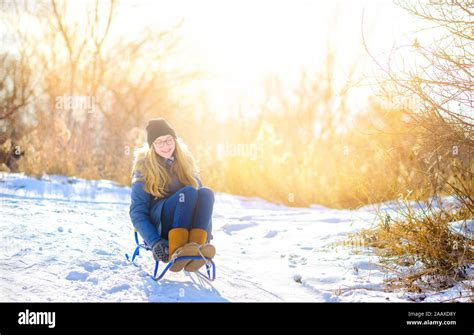 Cute Girl Sledding In A Snowy Winter Park Children Have Fun And Have