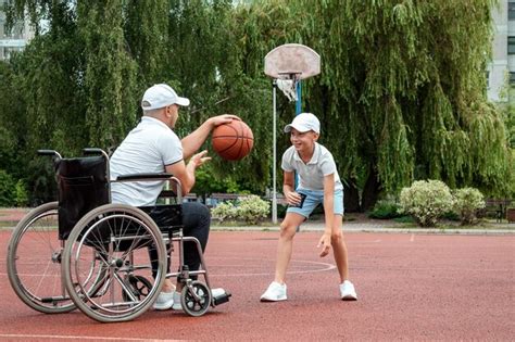 Premium Photo A Man In A Wheelchair Plays Basketball With His Son On