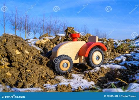 Wooden Tractor In An Earthy Field Farming Toy With Snow Stock Photo