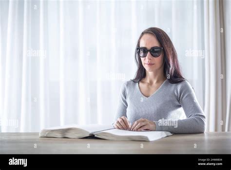 Blind Woman Reads Book In Braille On A Table In Front Of Her Stock