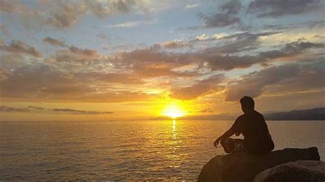 Man Sitting On Rock Watching Sunset Over Sea Sea Photography Sunset