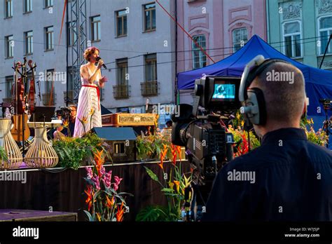 A singer singing on an outdoor stage during a benefit concert. A ...