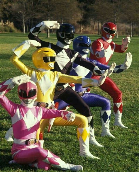 Five People In Power Rangers Costumes Sitting On The Grass