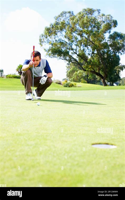 Male Golfer Lining Up The Putt Full Length Of Crouched Male Golfer On