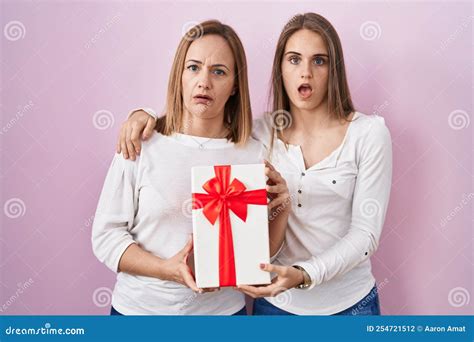 Middle Age Mother And Young Daughter Holding Mothers Day T In Shock Face Looking Skeptical