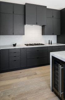 A Kitchen With Black Cabinets And White Counter Tops