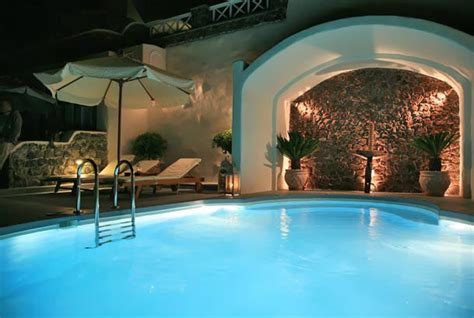 An Indoor Swimming Pool At Night With Lights On The Walls And Chairs