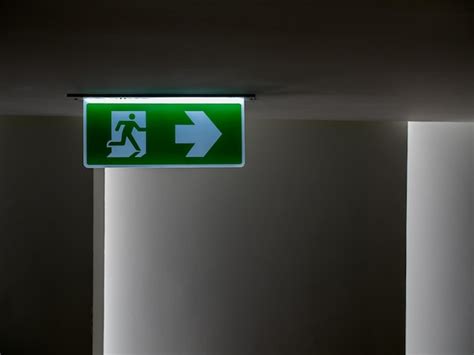 Premium Photo Green Fire Escape Sign Hang On The Ceiling In The Dark