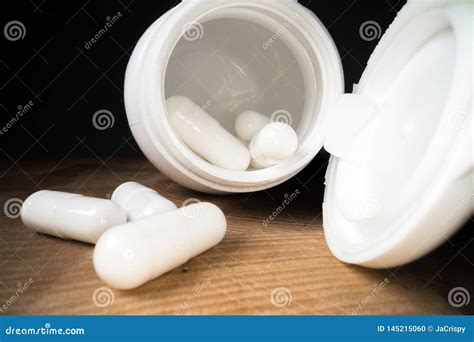 White Pills Or Capsules Next To Bottle On Wooden Table Background Drug