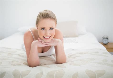 Natural Smiling Blonde Lying On Bed Touching Her Chin Stock Image