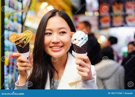 Young Female Model Eating Ice Cream Cone On Hong Kong Street Stock