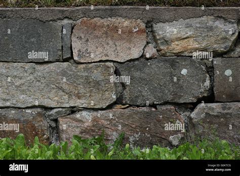 Old fashioned stone wall with grass on the ground Stock Photo - Alamy