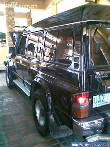 Nissan Patrol Safari VS 4x4 Black Van Parked In Front Of A Building