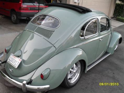 An Old Green Vw Bug Parked In Front Of A House