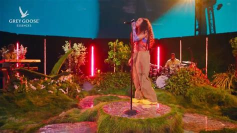 A Woman Standing On Top Of A Lush Green Field Next To A Microphone In