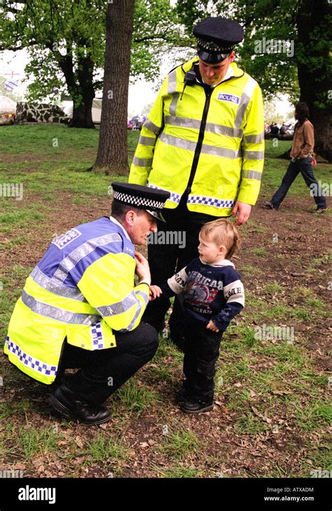 Policemen Helping A Lost Child Find His Parents At A Festival In Stock