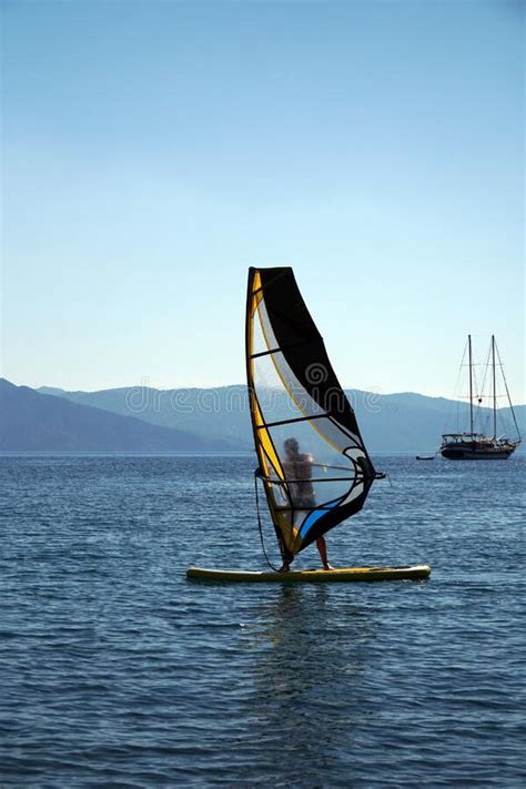 A Man On A Windsurf In The Bay With A Yacht In The Background Man