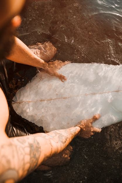 Homme Assis Sur Une Planche De Surf Blanche Dans L Eau Photo Gratuite