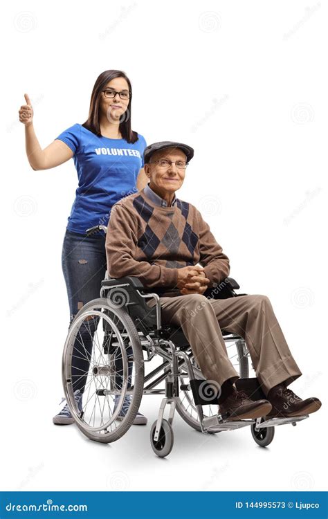 Young Woman Volunteer Pushing A Senior Man In A Wheelchair And Showing