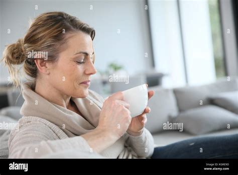 Mature Woman In Sofa Drinking Hot Coffee Stock Photo Alamy