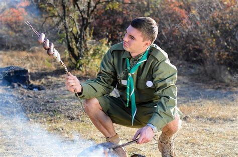 Boy Scout Cooking Sausages on Sticks over Campfire — Stock Photo © ampack #68883441