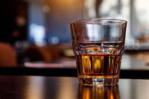 a glass of whiskey sitting on top of a wooden table