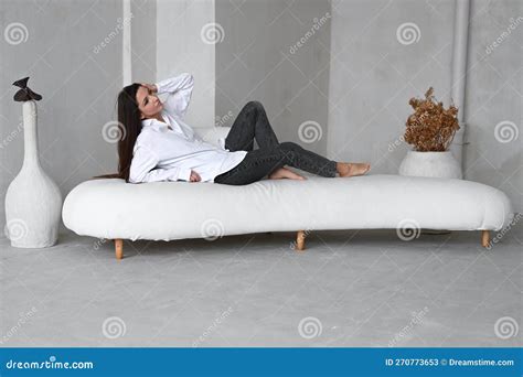 Good Looking Brunette Woman Posing While Lying On A Sofa In Studio