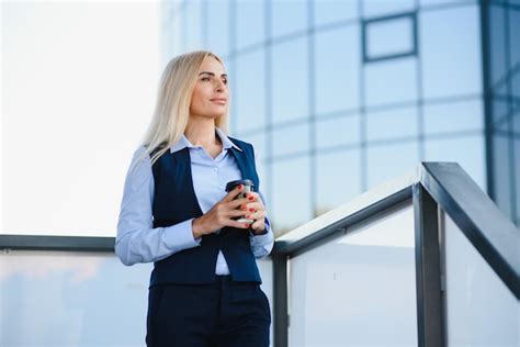 Hermosa mujer yendo a trabajar con café caminando cerca del edificio de