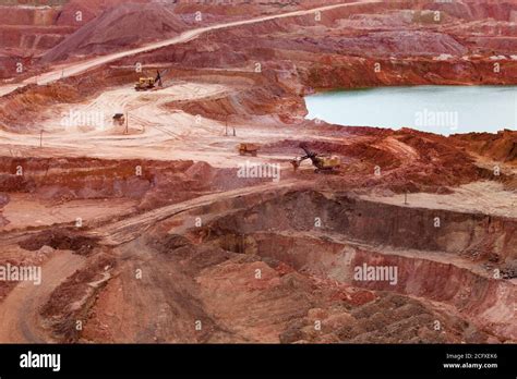 Aluminium Ore Quarry And Blue Lake In Bauxite Mine Yellow Excavators