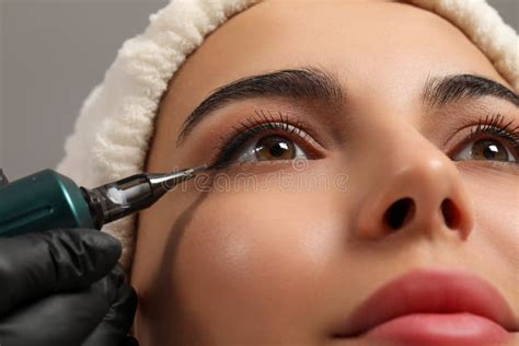 Young Woman Undergoing Procedure Of Permanent Eyeliner Makeup Closeup