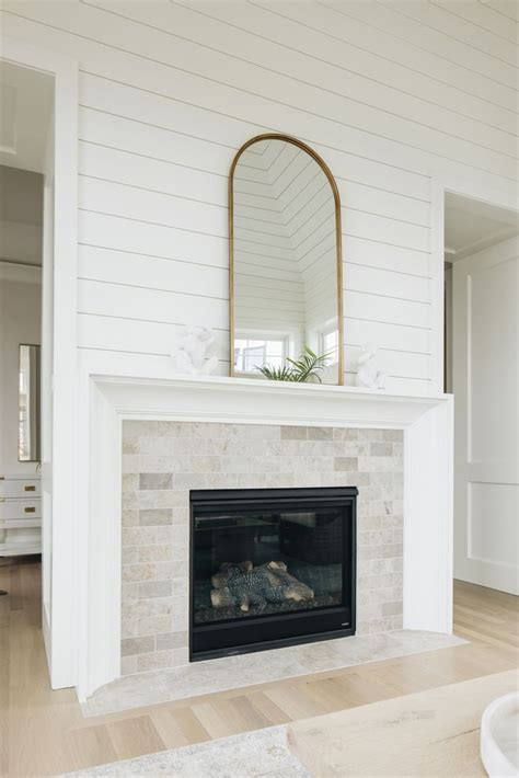 A White Fireplace With A Mirror Above It