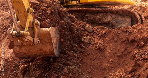 Backhoe working by digging soil at construction site. Bucket of backhoe ...