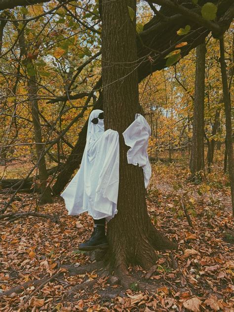 Two White Ghost Costumes Hanging From A Tree In The Woods With Leaves