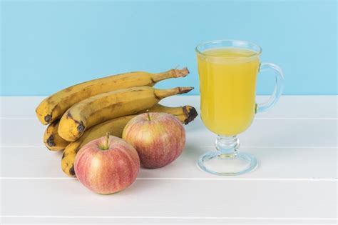 Premium Photo Fresh Bananas Apples With A Glass Of Juice On A White Table