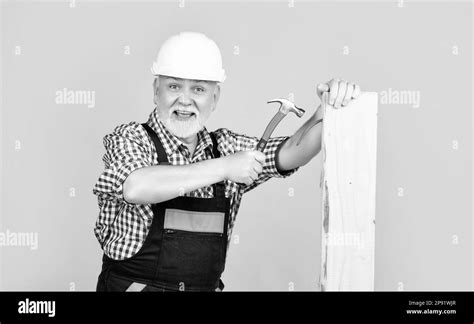 Cheerful Mature Man Woodworker In Helmet On Yellow Background Stock