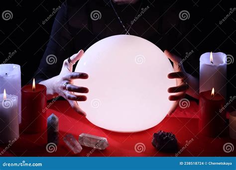 Soothsayer Using Glowing Crystal Ball To Predict Future At Table In