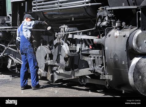 A Mechanic Worker Checking A Steam Locomotive On The Railroad Between