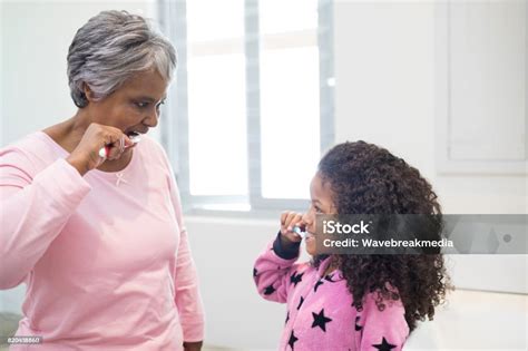 Grandmother And Granddaughter Brushing Teeth In The Bathroom Stock