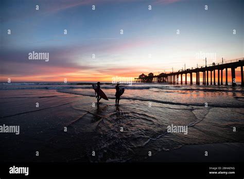 Silhouettes Of Surfers At Huntington Beach Pier At Sunset California