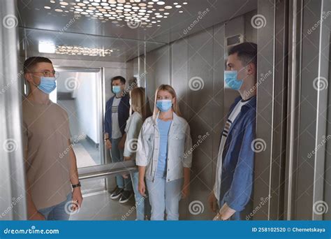 Group Of People With Face Masks In Elevator Protective Measure Stock