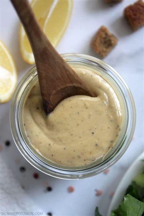 A Jar Filled With Dressing Next To Sliced Lemons