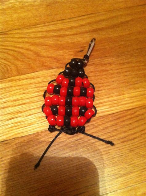 A Red And Black Beaded Bug Sitting On Top Of A Wooden Table