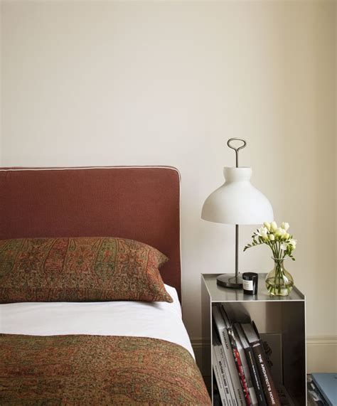 A Bed Sitting Next To A Nightstand With A Lamp And Books On Top Of It