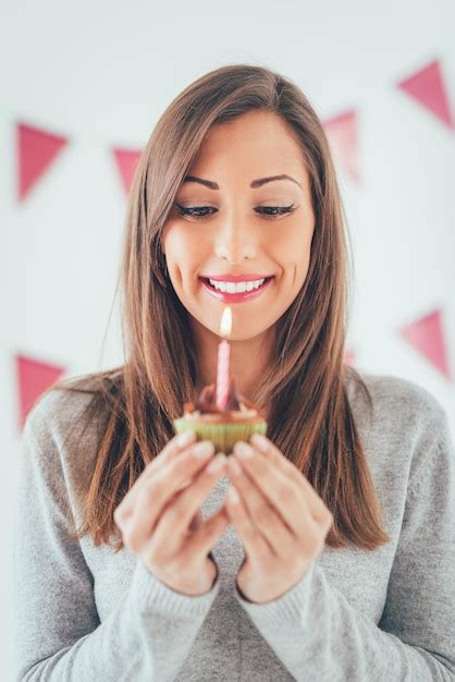 Hermosa joven sonriente mirando hacia abajo a un pequeño pastel de