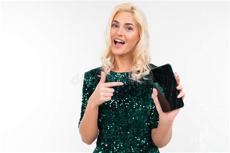 Blonde Meid In Een Groene Glanzende Jurk Toont Een Blanco Smartphone Display Met Een Mockup Op