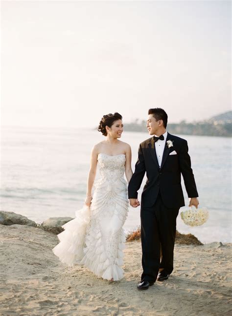 A Bride And Groom Walking On The Beach