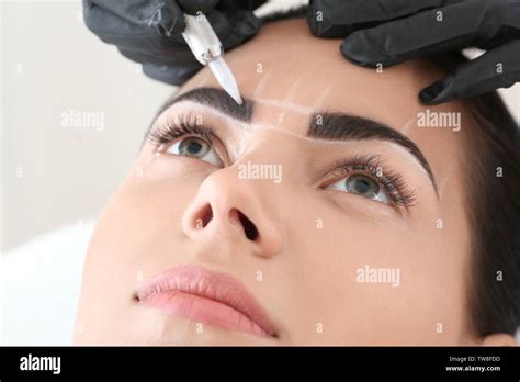 Young Woman Undergoing Procedure Of Eyebrow Permanent Makeup In Beauty