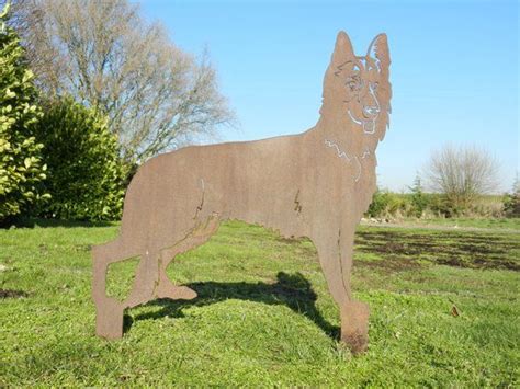 A Metal Dog Statue In The Grass With Trees In The Background