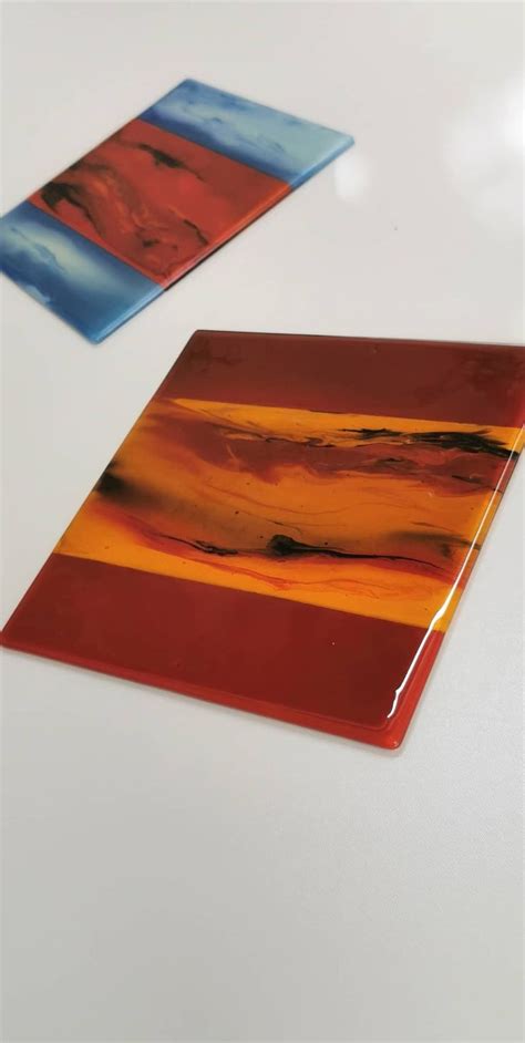 Two Pieces Of Colorful Glass Sitting On Top Of A White Table Next To