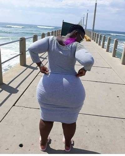 A Woman Is Standing On A Pier By The Ocean With Her Back To The Camera